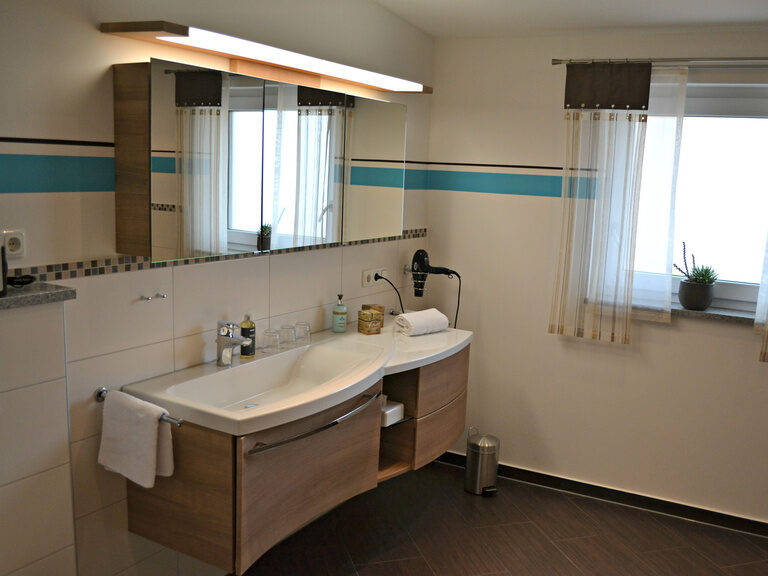 Stilvolles Badezimmer mit Holz-Waschtisch und großem Spiegelschrank in Premium-Appartement