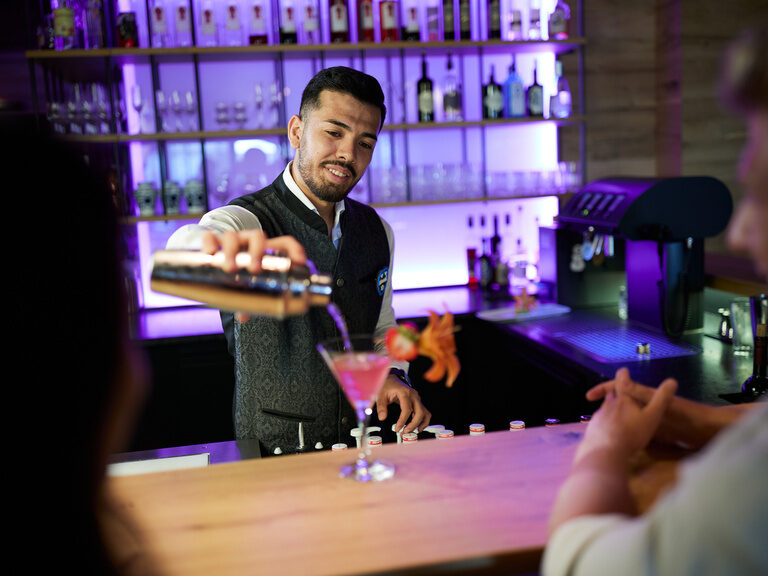 Barkeeper serviert frischen Cocktail aus dem Cocktailshaker in Emy´s Bar