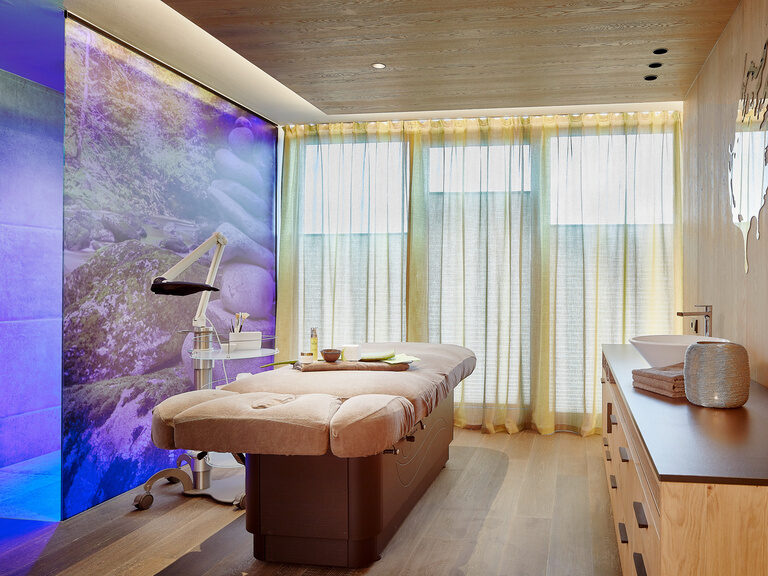 Moderner Spa-Behandlungsraum mit Beleuchtung an Wand, Liege und Waschbecken