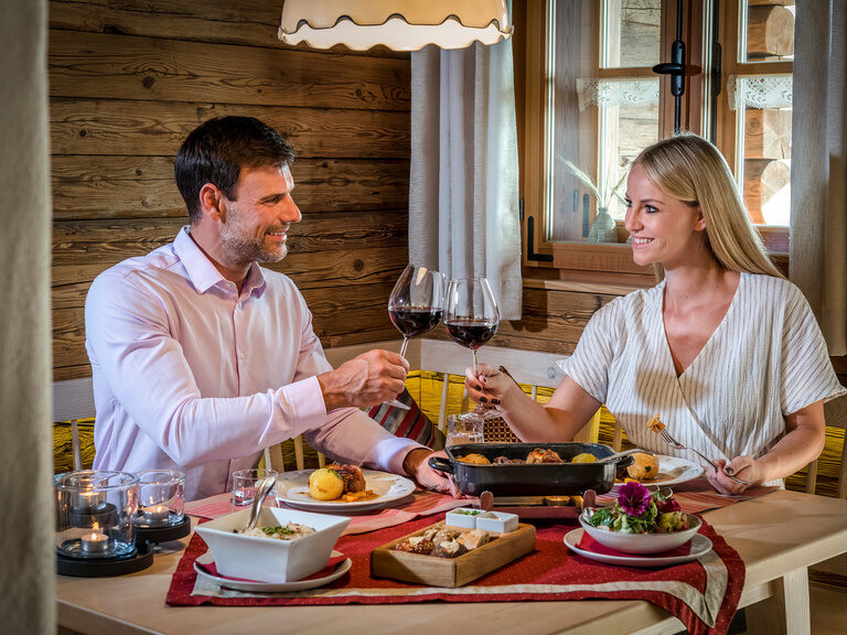 Pärchen genießt im Luxus Chalet Bayern ein traditionelles Bayerisches Gericht